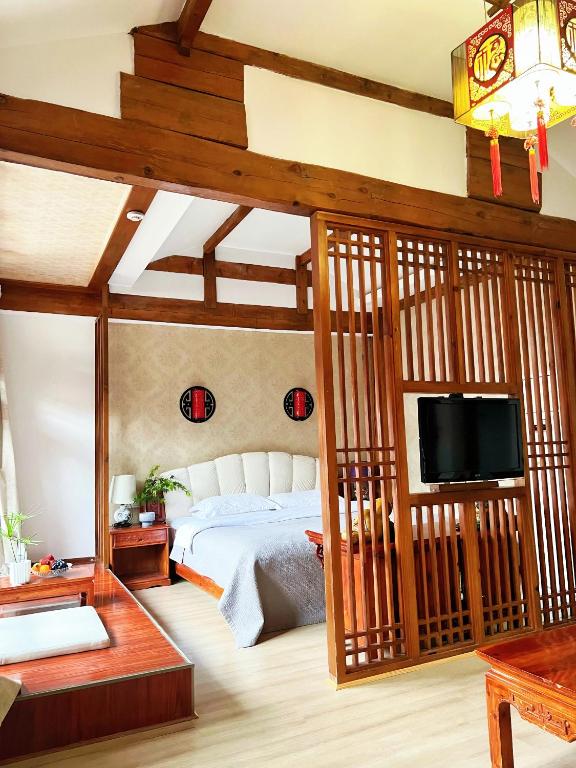 a bedroom with a bed and a flat screen tv at 原乡文苑客栈 in Lijiang
