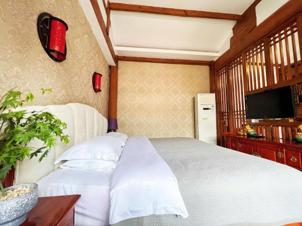 a bedroom with a white bed and a tv at 原乡文苑客栈 in Lijiang