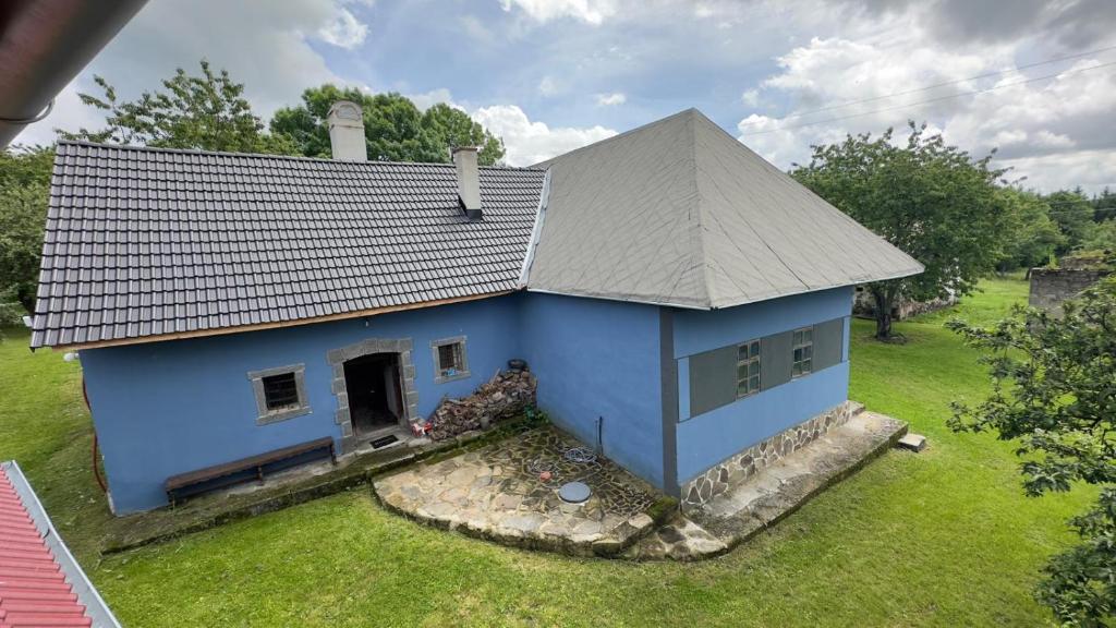 a blue house with a gray roof on a yard at Modrá chalupa in Pliešovce