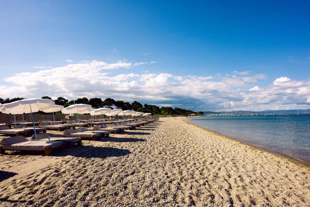 伊埃爾的住宿－Le Hameau Des Pesquiers Ecolodge & Spa, Curio Collection By Hilton，海滩上的一排遮阳伞和椅子