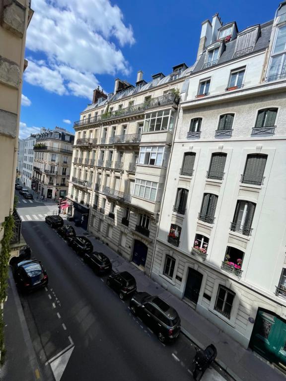 une rue avec des voitures garées devant un bâtiment dans l'établissement Apparemment au cœur de Paris, à Paris