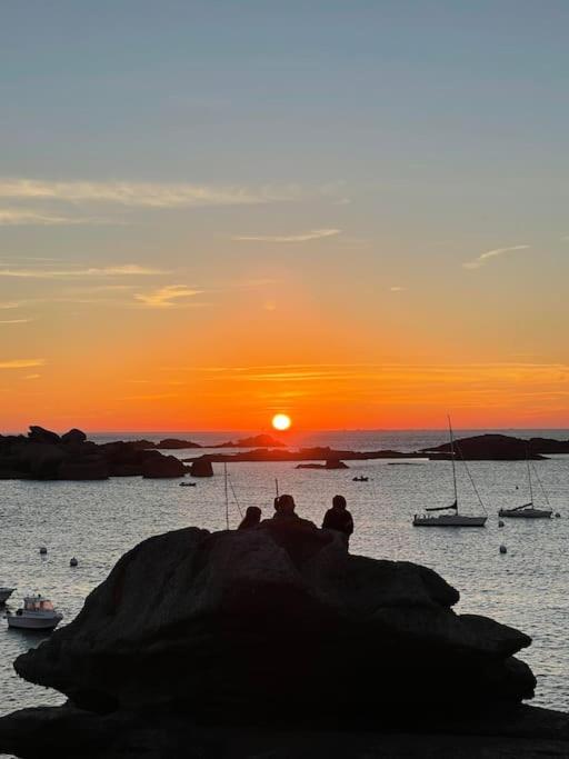 - un groupe de personnes assises sur un rocher en regardant le coucher du soleil dans l'établissement Vacances à 50m de la plage et de la mer, à Trégastel