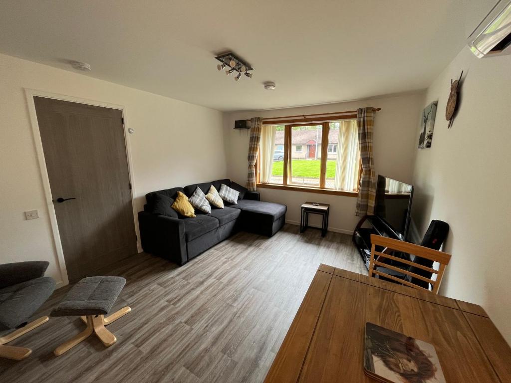 a living room with a couch and a table at The Wee Hoose near Loch Ness, private garden, private parking in Drumnadrochit