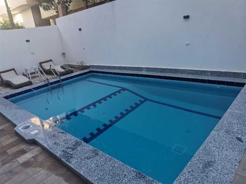 a swimming pool with blue water and two chairs at Luxor family in Luxor