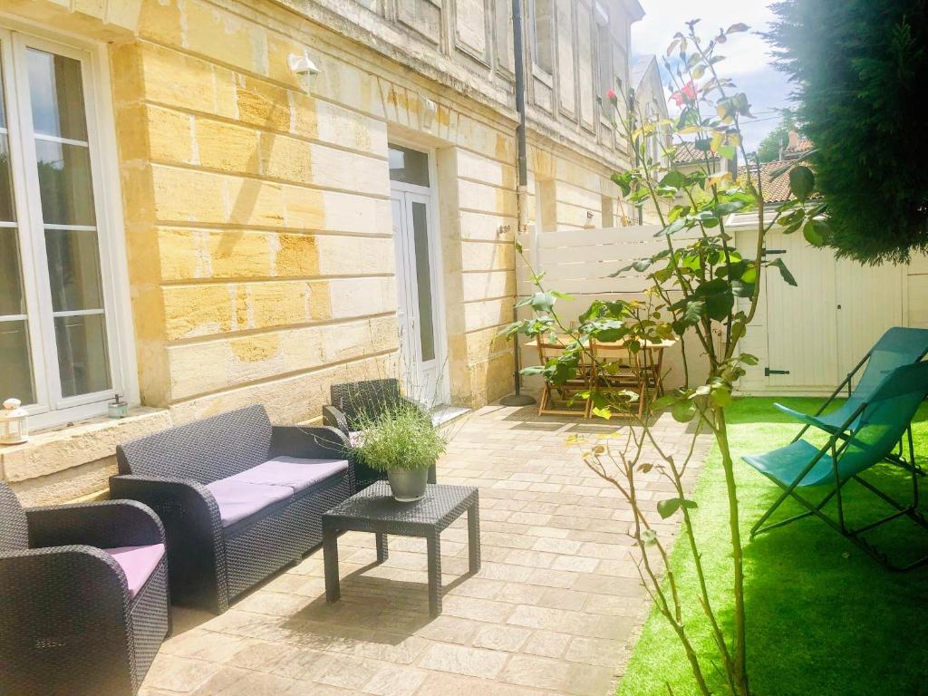 un patio avec des chaises, un canapé et une table dans l'établissement Maison de ville 5 min de la gare, à Bordeaux