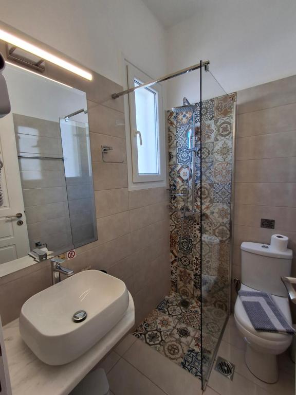 a bathroom with a toilet and a sink and a shower at RESTIA in Agios Petros