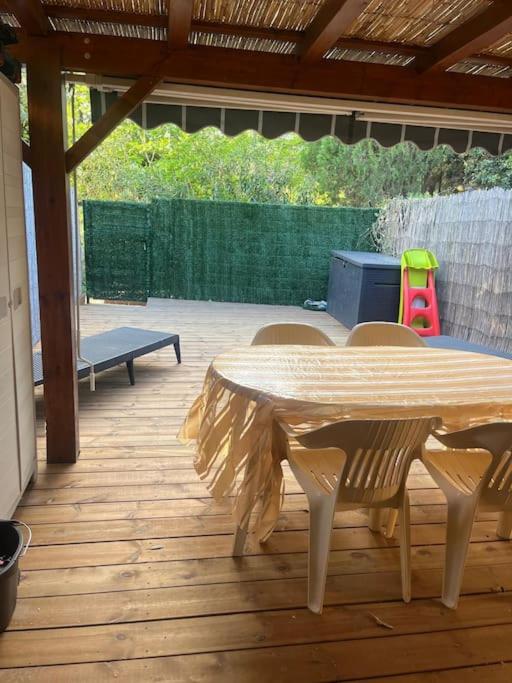 une table et des chaises en bois sur une terrasse avec une table dans l'établissement Maisonette 6 pers proche plage, à Argelès-sur-Mer