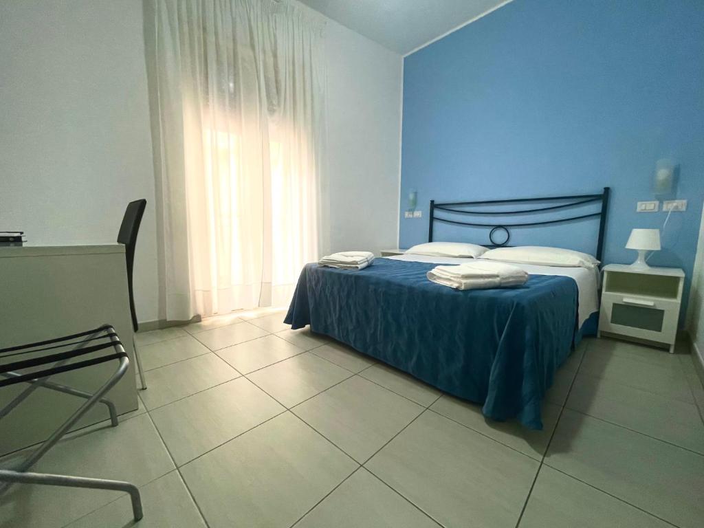 a blue bedroom with a bed and a window at Maniel Beach Hotel in Letojanni