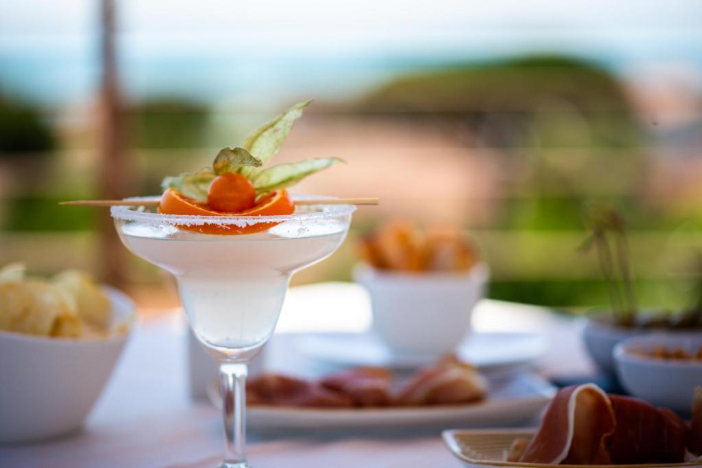 a drink in a glass on a table with plates of food at Zen Hotel Versilia in Marina di Pietrasanta