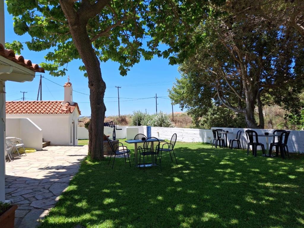 a patio with tables and chairs under a tree at RESTIA in Agios Petros