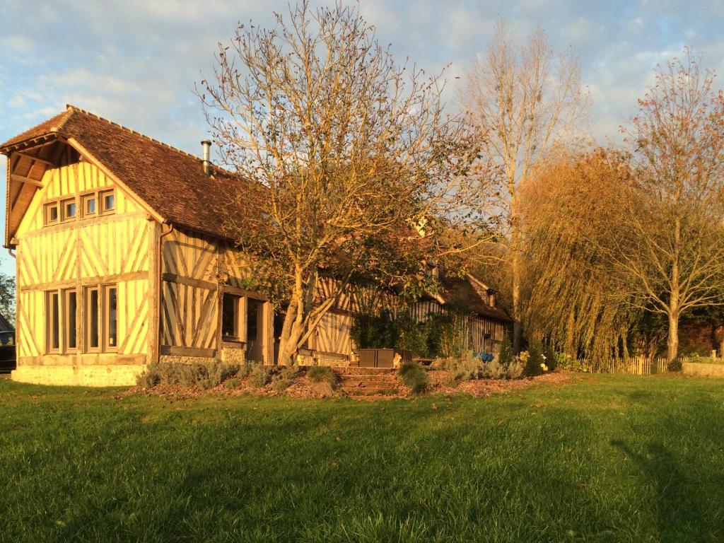 a large wooden house in a field with trees at Maison XVIIIe avec vue panoramique exceptionnelle - 12 pers au coeur du Pays d'Auge in Le Renouard