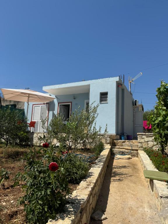 a house with a garden with flowers and an umbrella at Vila Bedro in Sarandë