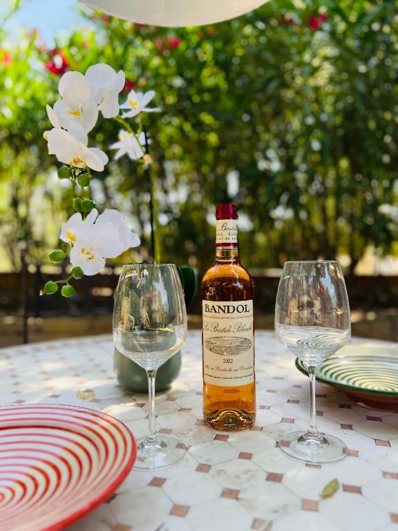 - une bouteille d'alcool assise sur une table avec deux verres à vin dans l'établissement Au rythme des cigales, à Laouque