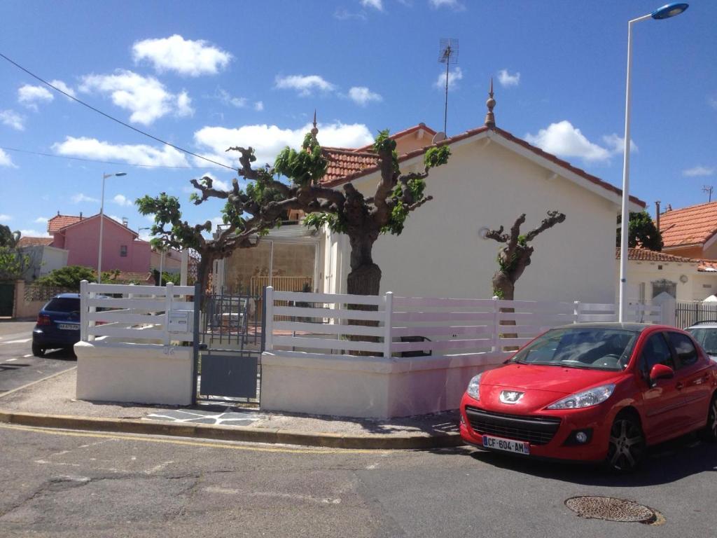 une voiture rouge garée devant une maison dans l'établissement Maison typique Canétoise, à Canet