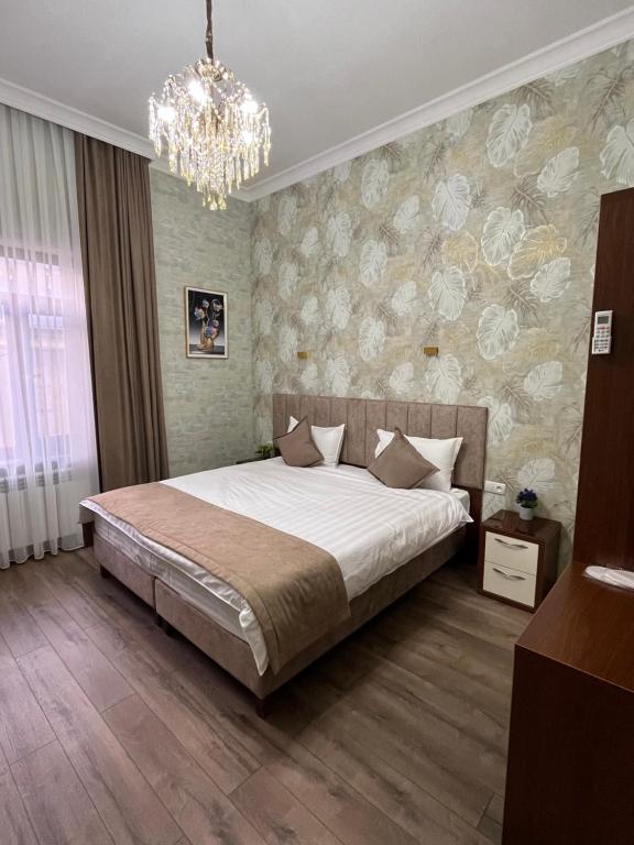 une chambre avec un grand lit et un lustre dans l'établissement Vasiev's Hotel, à Samarcande