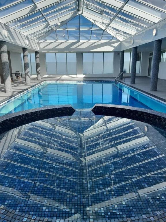 a large swimming pool with blue tiles in a building at Chalet 26 Widemouth Bay in Bude