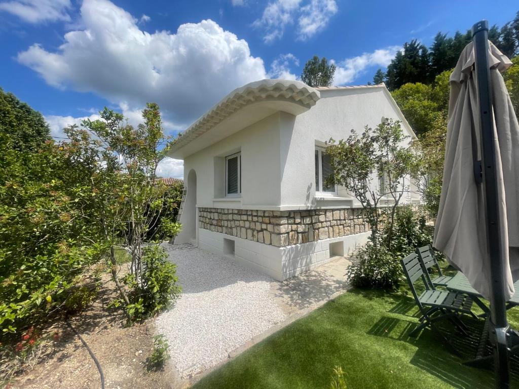 a small white house with a patio and an umbrella at La maison des Lilas in Aix-en-Provence
