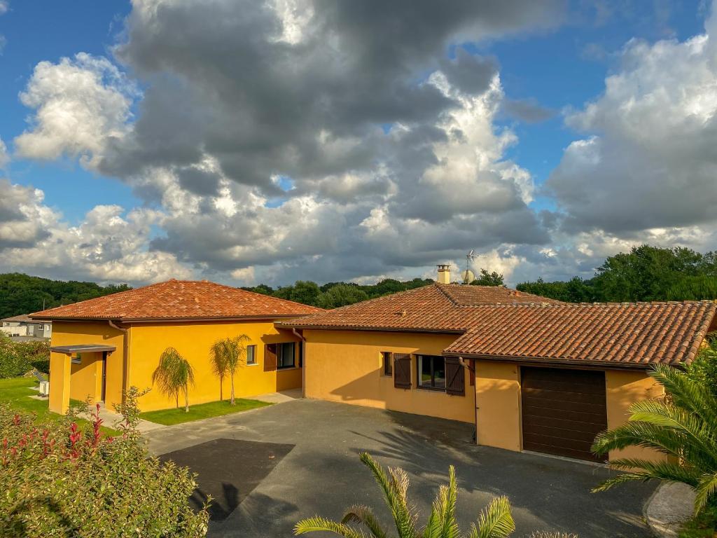 une maison jaune avec une allée devant elle dans l'établissement Maison mitoyenne, 2 chambres, 4 personnes, à Saint-Martin-de-Seignanx