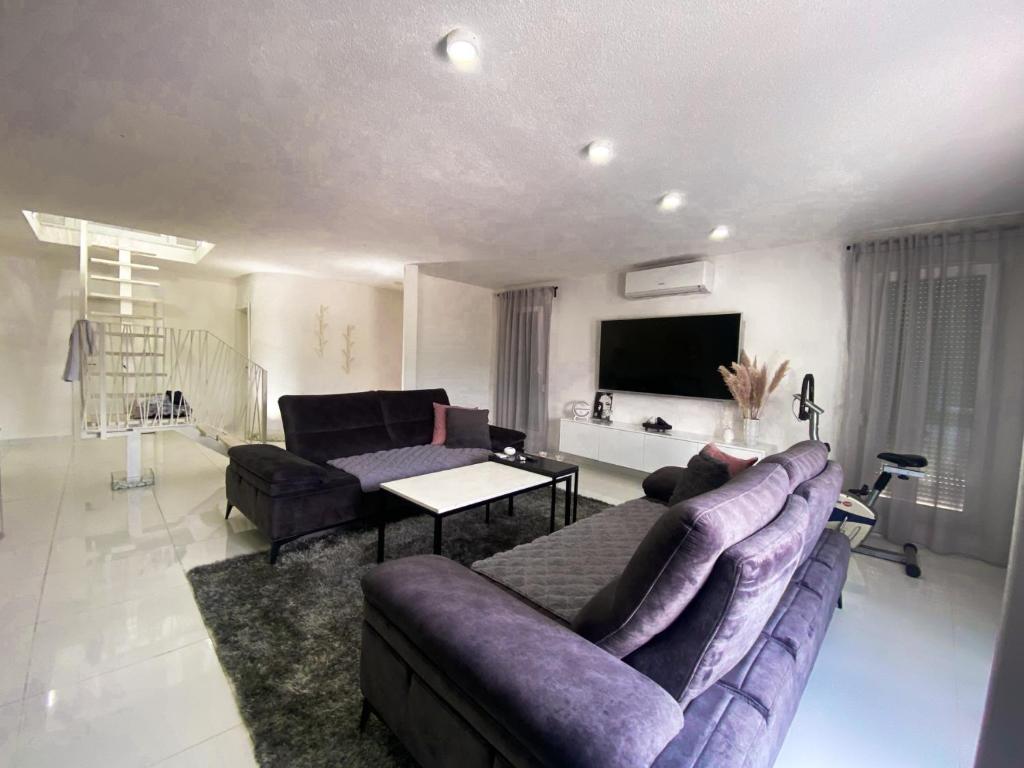 a living room with a purple couch and a tv at Villa La Familia in Bihać