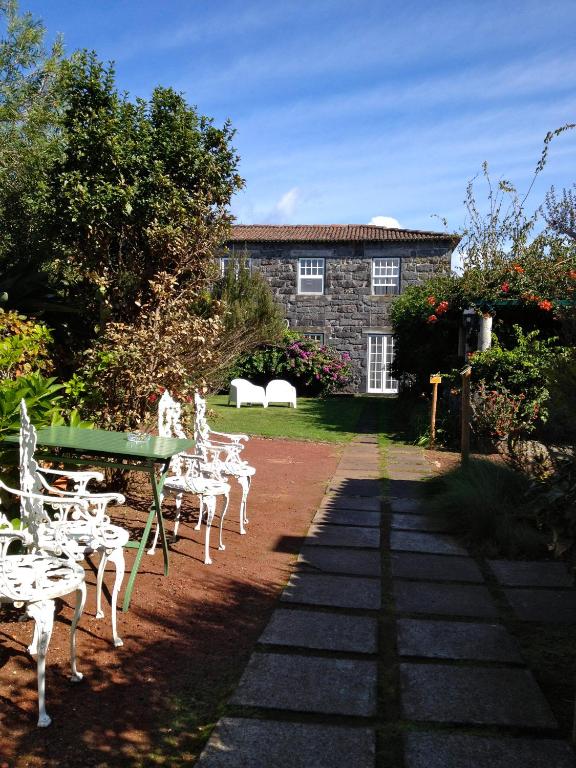 a garden with white chairs and a table and a building at Quinta das Buganvílias in Castelo Branco