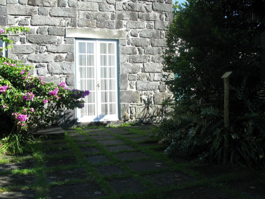 a stone building with a white door and flowers at Quinta das Buganvílias in Castelo Branco