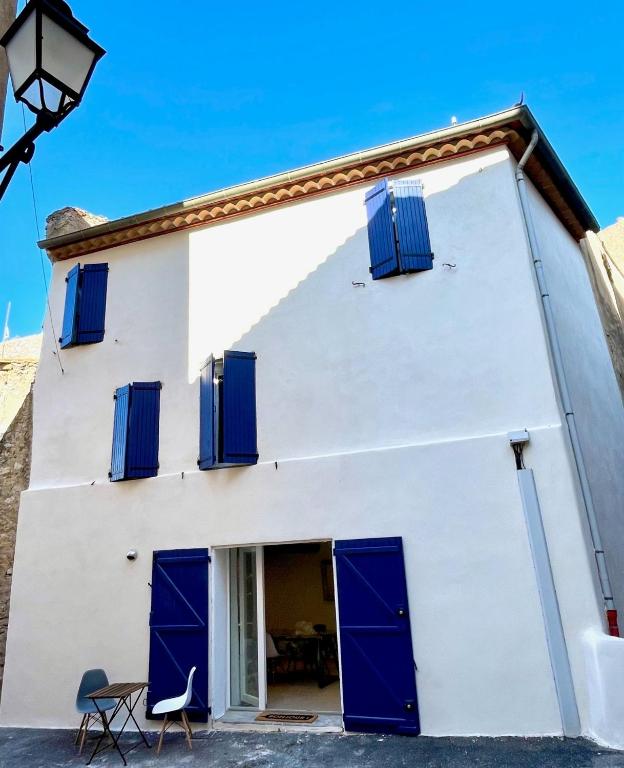 une maison blanche avec des volets bleus et une chaise dans l'établissement Gite de la Palme, à Lapalme