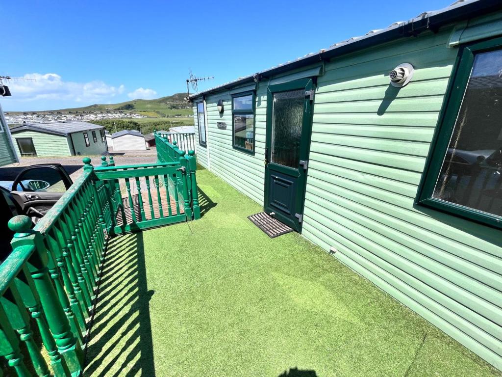 una casa verde con porche y puerta en Van number 123 Beautiful Caravan sleeps 4 to 6 en Aberystwyth