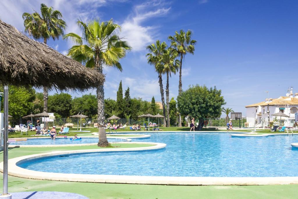a swimming pool at a resort with palm trees at Bungalow Pink Palm beach in Torrevieja