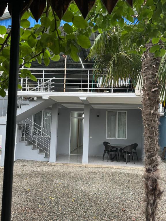 a building with a table and chairs and a palm tree at Nika House in Ureki