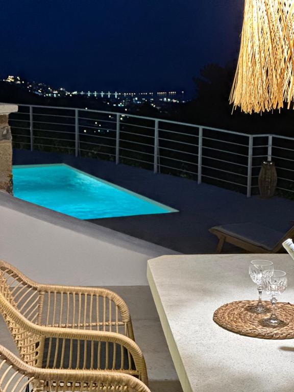 a table and chairs on a balcony with a pool at Villa Koukounaria in Skopelos Town