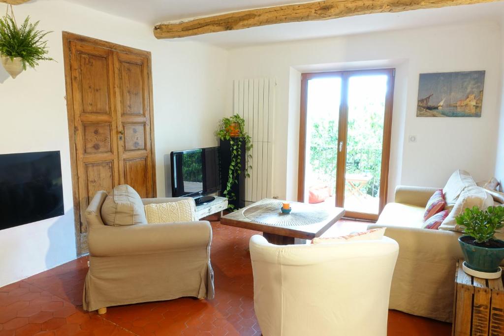 un salon avec des canapés, une table et une télévision dans l'établissement Grande maison de village 200 m2 calme tout confort, à Gréolières