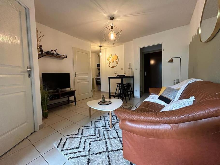 un salon avec un canapé en cuir marron et une table dans l'établissement Le Green Pont Jumeaux - T2 - Parking - Vue Canal, à Toulouse