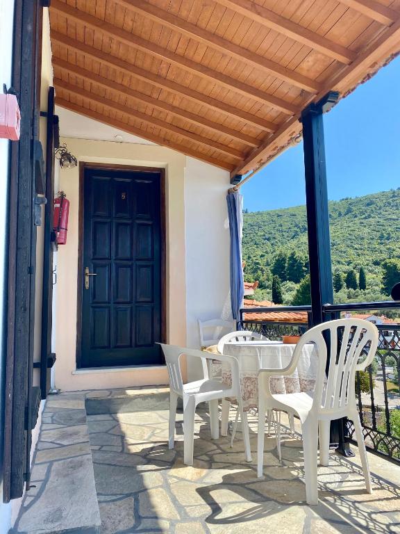 a patio with white chairs and a table and a door at Betsanis Stafylos Apartments in Stafylos