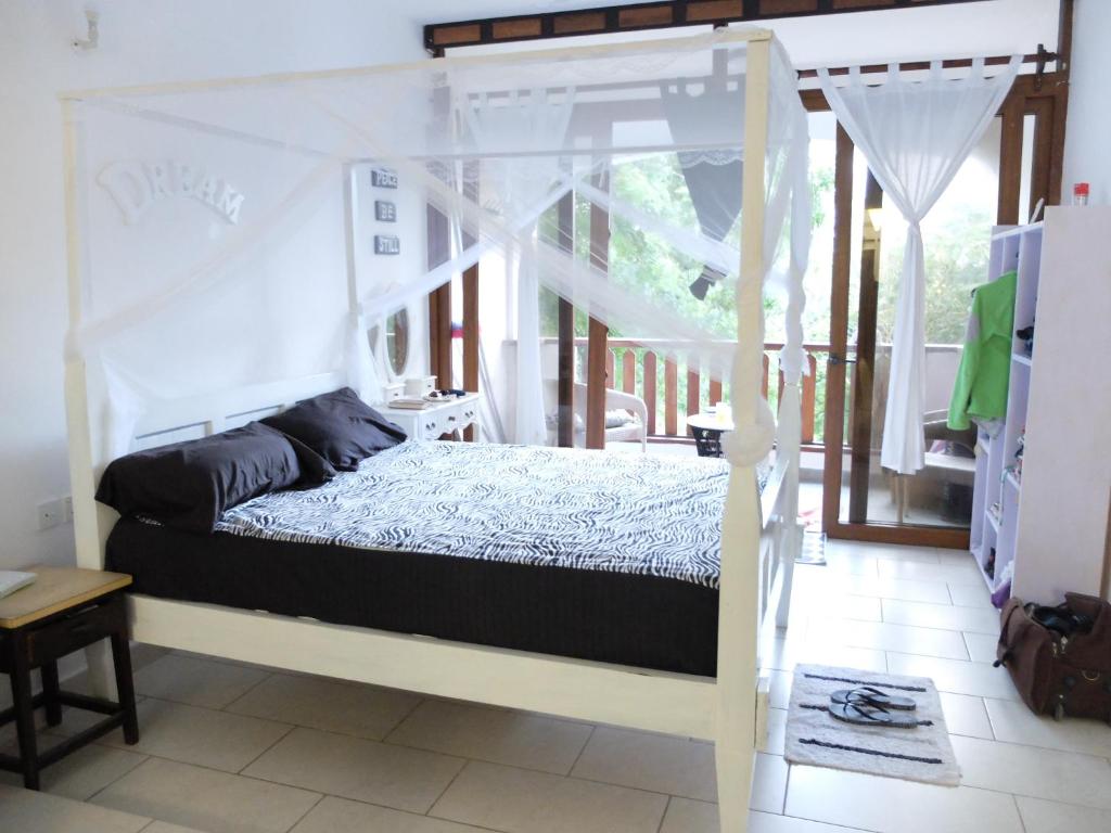 a bedroom with a canopy bed and a balcony at Restful Beach Front studio-Diani in Diani Beach