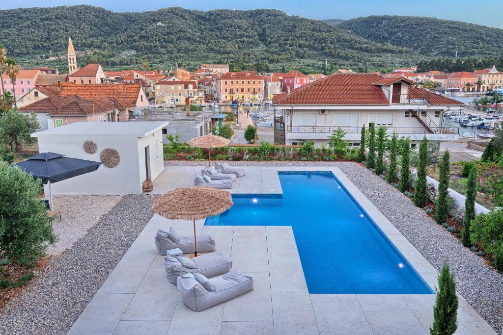 a pool with chairs and umbrellas next to a city at Hvar luxury Villa and pool with view in heart of Stari Grad in Stari Grad