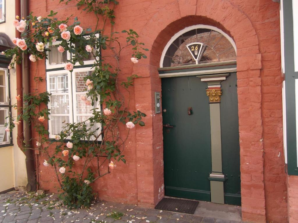 eine grüne Tür in einem Backsteingebäude mit Rosen in der Unterkunft Gast in Hedwigs Haus auf dem Meere in Lüneburg