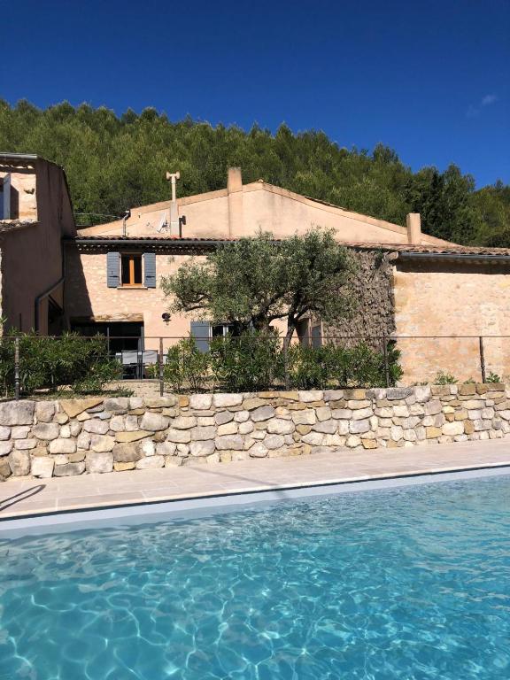 une maison avec un mur en pierre et une piscine dans l'établissement Entre lavande et oliviers, à Plaisians