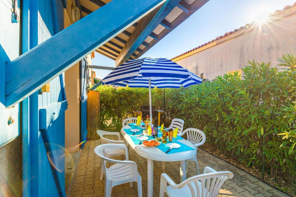 een tafel met een blauwe en witte parasol en stoelen bij Lagrange Vacances Les Maisonnettes in Sainte-Marie-Plage