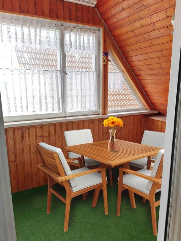 a wooden table and chairs in a room with windows at Wohnung Beth im Dachgeschoss mit Balkon in Lonnerstadt