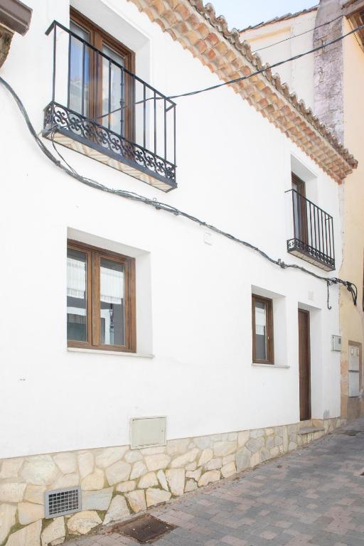 a white house with windows and a stone wall at Casa Rural La Rosalia in Cogolludo