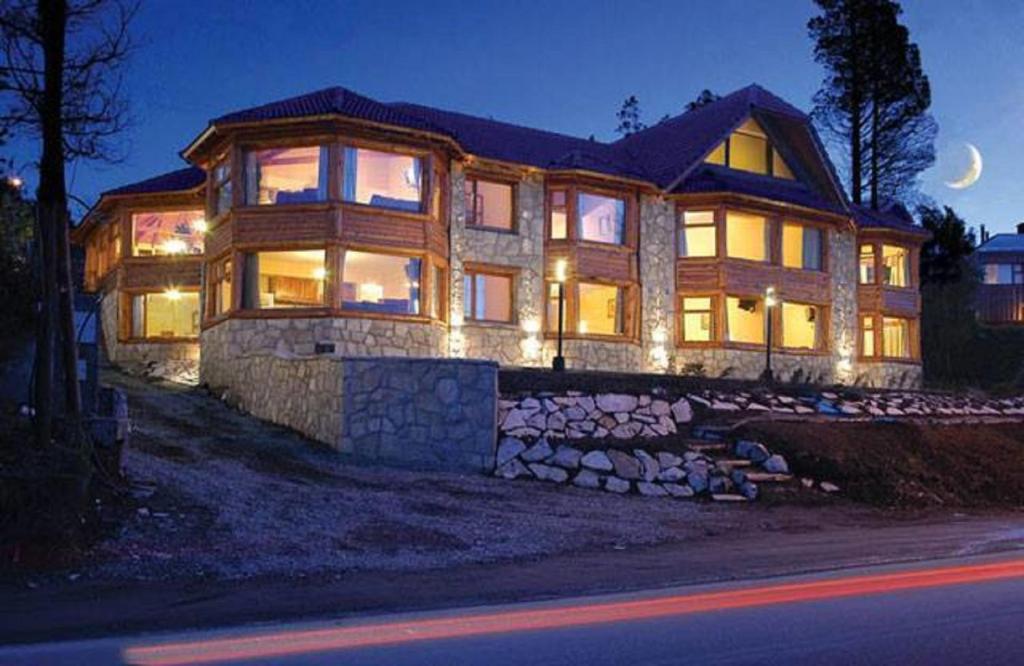une grande maison éclairée la nuit dans l'établissement Apart Altos Del Nahuel, à San Carlos de Bariloche