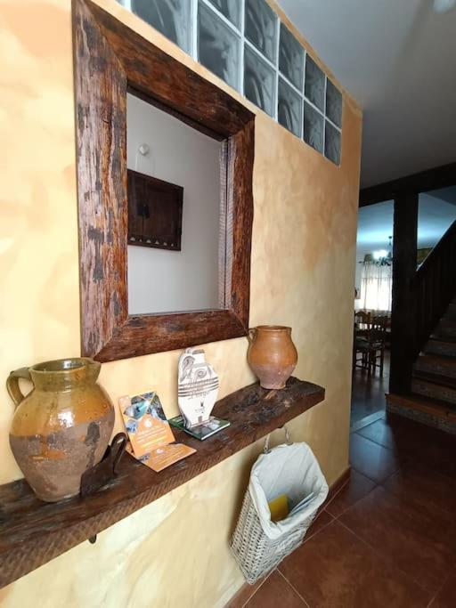 a mirror on a wall with vases on a shelf at Casa Las Peñuelas in Priego