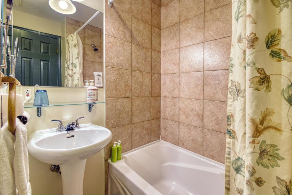 a bathroom with a sink and a bath tub at Auberge Le Lupin-Self Check-in in Mont-Tremblant