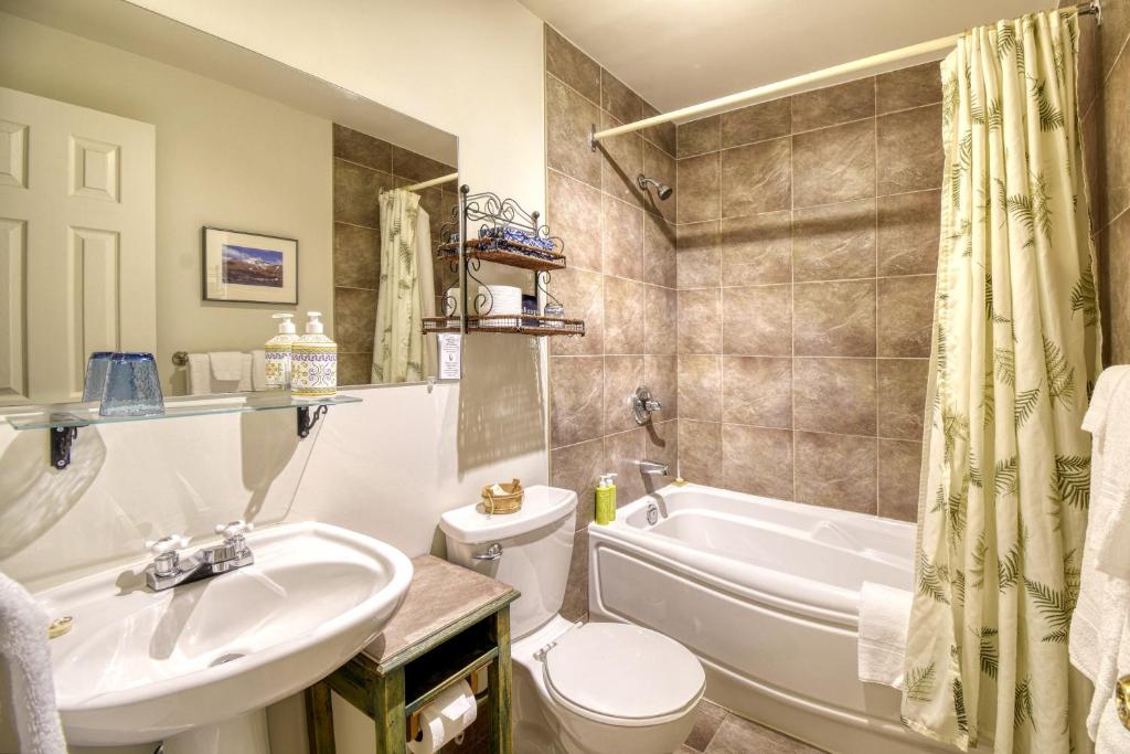 a bathroom with a sink and a tub and a toilet at Auberge Le Lupin-Self Check-in in Mont-Tremblant