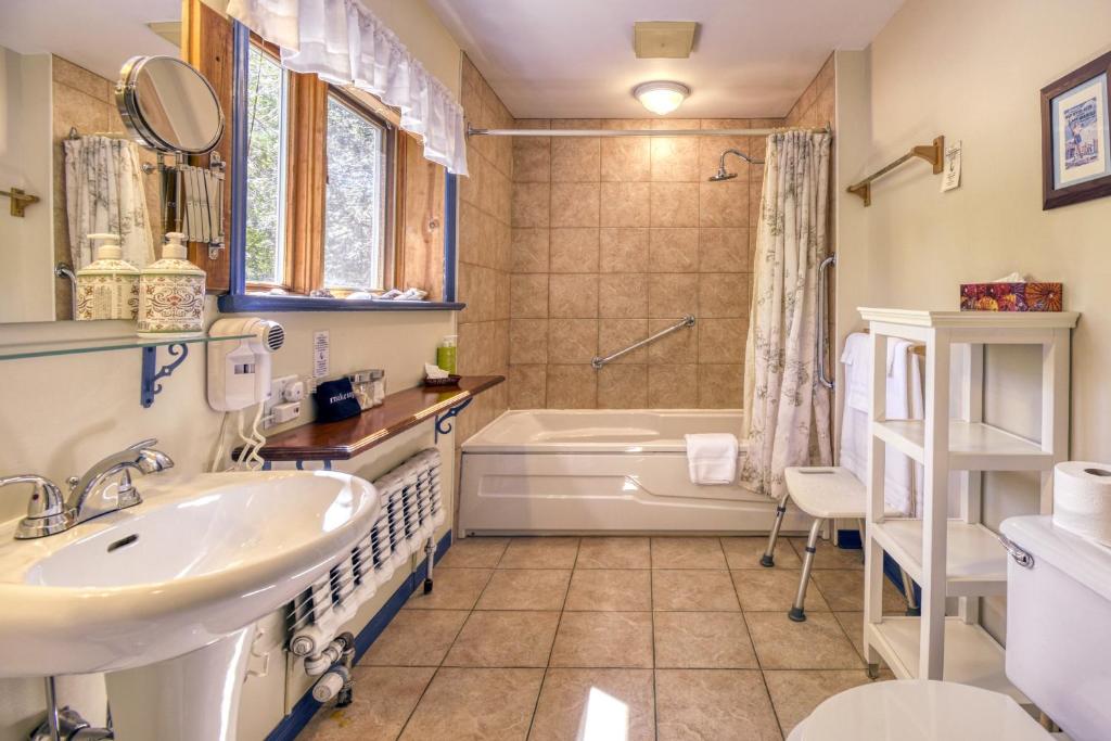 a bathroom with a sink and a tub and a toilet at Auberge Le Lupin-Self Check-in in Mont-Tremblant