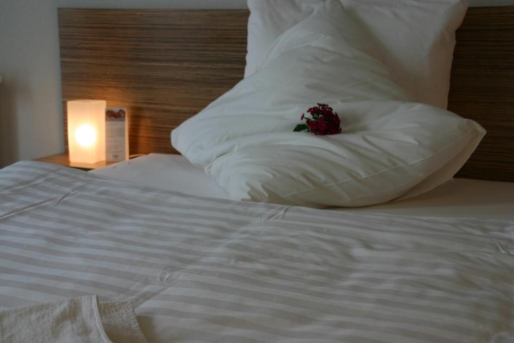 a white bed with a pillow with a flower on it at Ferienhof Dittrichs Erben in Radebeul