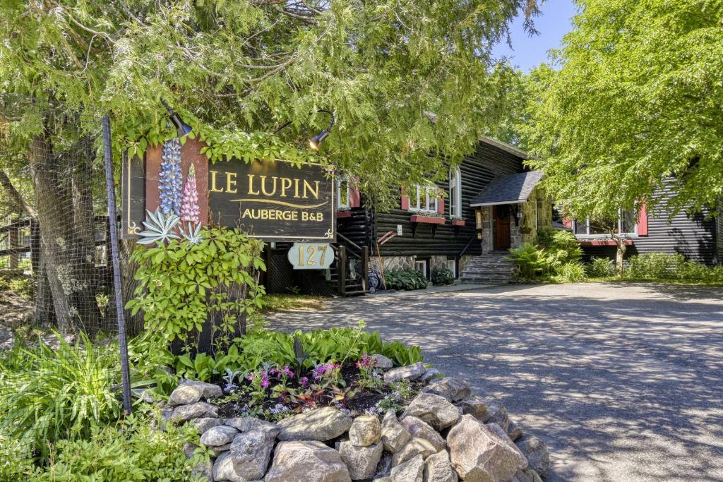 a sign for the entrance to a lodge with flowers at Auberge Le Lupin-Self Check-in in Mont-Tremblant