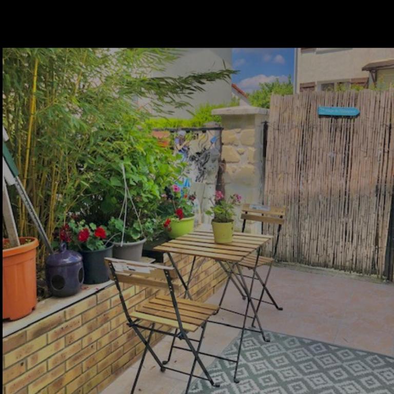 un patio avec une table, des chaises et des plantes en pot dans l'établissement T2 jardin privatif 20mn de Paris centre -Disneyland, à Villiers-sur-Marne