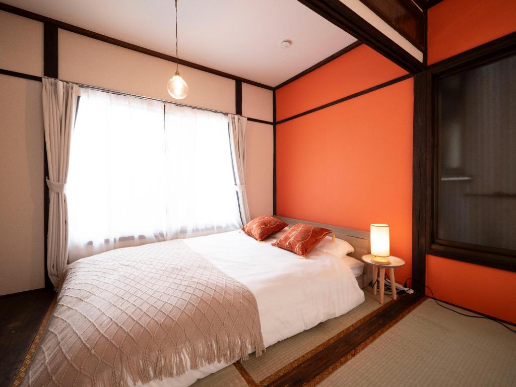 1 dormitorio con paredes de color naranja y 1 cama con ventana en 6min to subway, Skytree,Ueno,Asakusa within 20min, en Tokio
