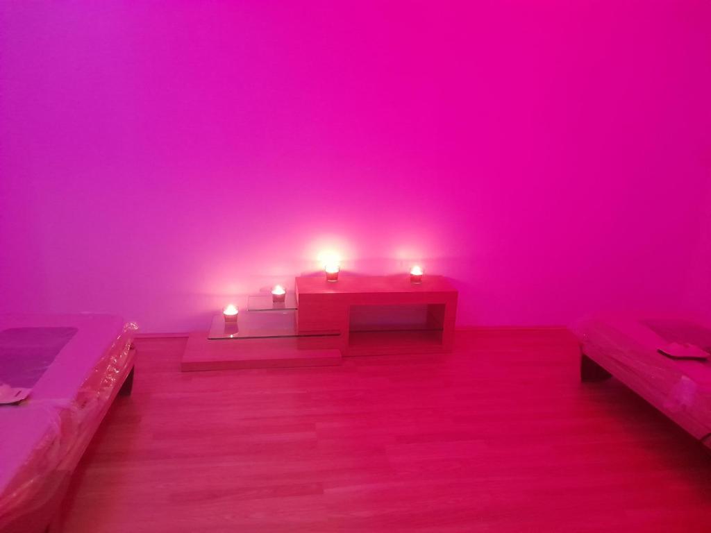 ein rosa Zimmer mit zwei Bänken und zwei Kerzen in der Unterkunft Le Zébresse in Combrand